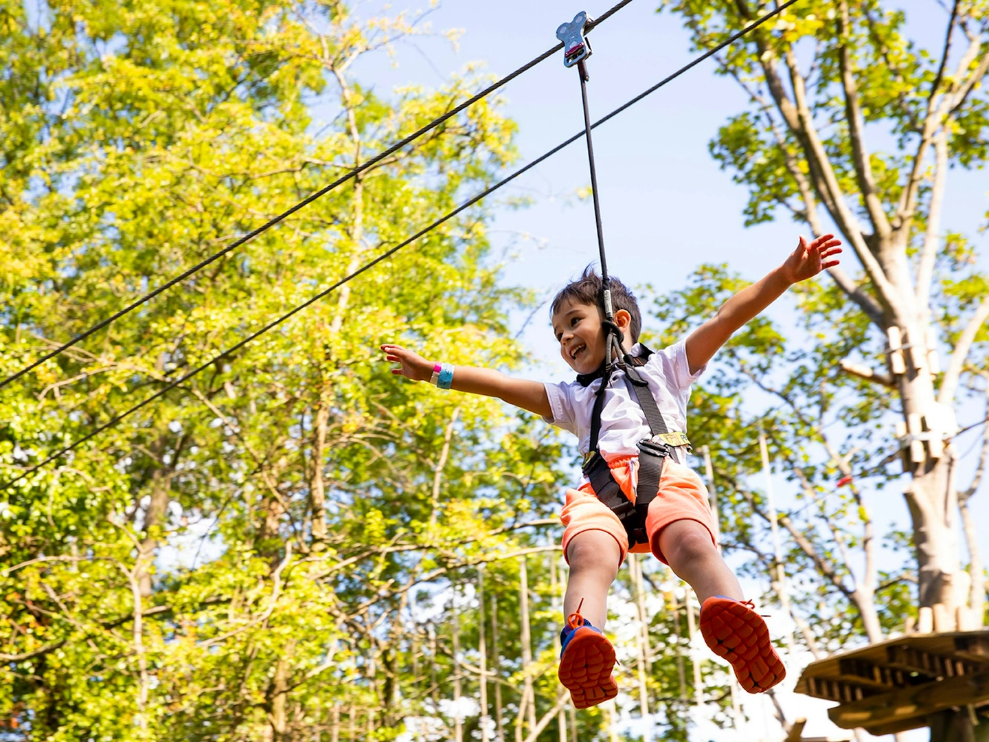 Young person on a zipline while smiling.