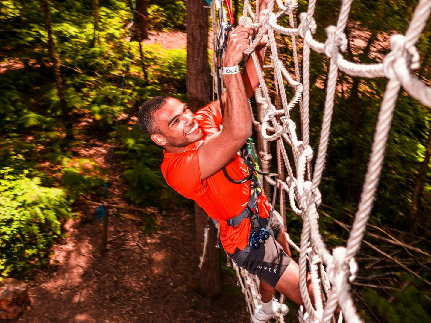 A man climbs a cargo net on a Go Ape high ropes course