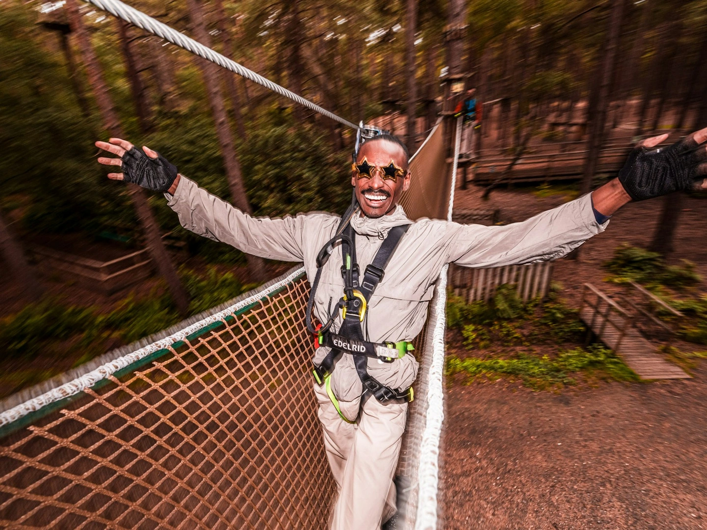 A man holds out his arms and smiles ona fun day out in the treetops at Go Ape